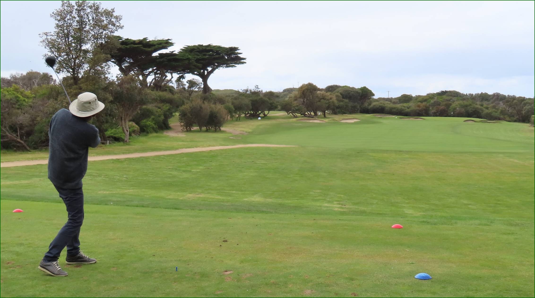 A golf course with trees and a blue sky

Description automatically generated