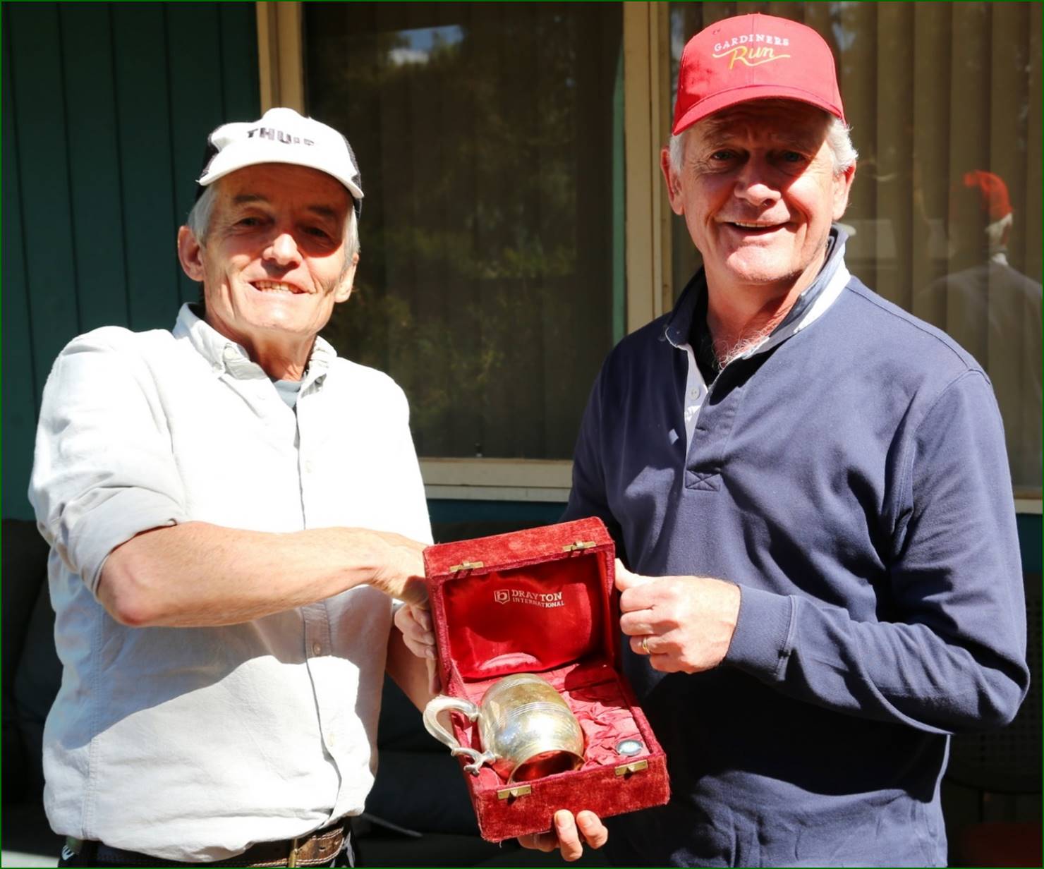 Two men holding a box with a silver object

Description automatically generated