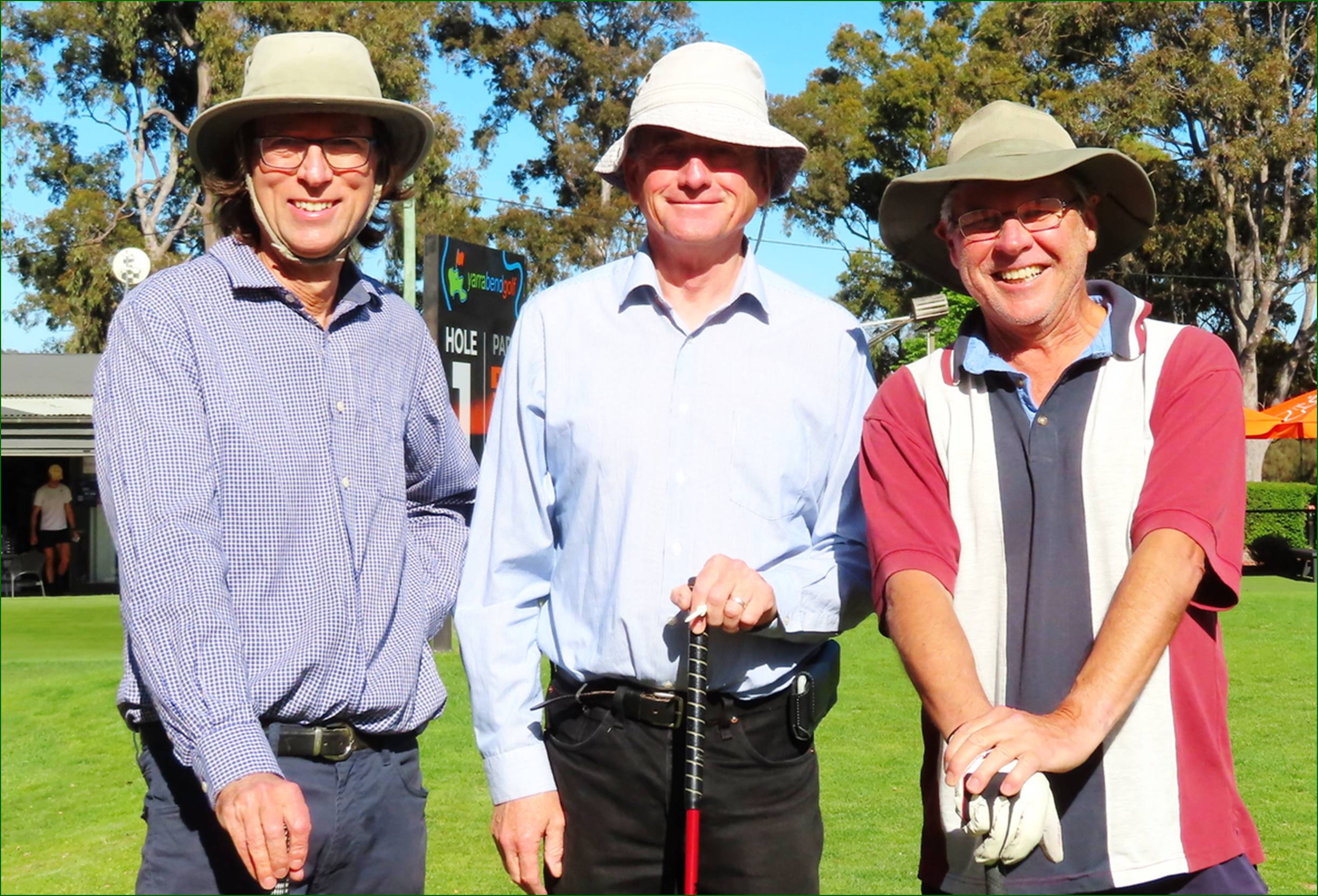 A group of men wearing hats and standing on a golf course

Description automatically generated